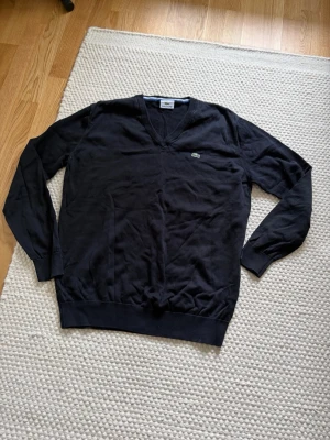 Lacoste tröja - Säljer denna Lacoste tröja som är i mycket bra skick, knappt använd. Storlek 5 motsvarar M/L Nypris: 1499kr Mått: Axel-Axel 46cm Armhåla-Armhåla 51cm  Längd 65cm