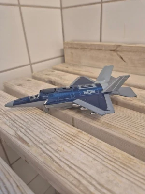 Blå modellflygplan i plast - Säljer ett detaljerat modellflygplan i blått och grått med vita dekaler och amerikanska flygvapnets symbol. Planet är gjort av plast och har små missiler under vingarna samt cockpit med pilotfigur.