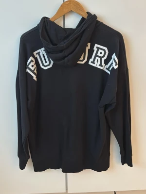 Svart hoodie - Snygg svart hoodie med stor vit text 'FUTURE' över ryggen. Klassisk passform med huva och känguruficka framtill. Tillverkad i mjukt material som känns skönt mot huden. Gåva vid köp!🎁