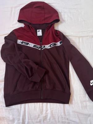 Nike tech vinröd - Nike tech hoodie. Köpt 2022 men inte använd sedan sent 2022 - tidigt 2023. Inga hål eller stora defekter men materialet är lite slitet. 137-147 cm.