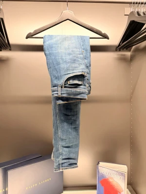 Tiger of Sweden - Snygga ljusblå jeans med klassisk femficksdesign och raka ben. Jeansen har en brun läderpatch bak i midjan och är tillverkade i mjukt denimtyg. Perfekta för en avslappnad och trendig look.