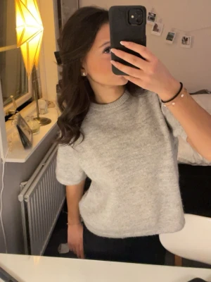 Ljusgrå oversized stickad tröja - Mysig ljusgrå stickad tröja med oversized passform och kortare ärmar. Tröjan har rund halsringning och är enkel att matcha med olika stilar. Perfekt för dig som gillar en avslappnad look. Gina tricot young 152 