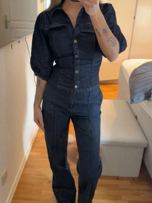 Mörkblå denim jeans set  - Snygg mörkblå jeans set tröjan är puffiga trekvartsärmar och knappar framtill. Setet har klassiska jeanssömmar, krage och raka ben. Perfekt för dig som vill sticka ut med en cool och trendig look. Toppen är i storlek xs men passa mig som bruka ha xs-S och byxorna i storlek 34 passa mig som bruka ha 36. Säljer endast hela setet. Endast använd en gång!!