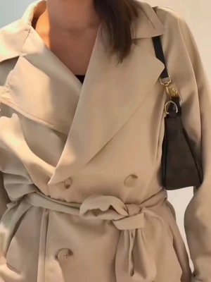 Beige trenchcoat  - Stilren beige trenchcoat med dubbelknäppning och brett slag. Jackan har ett matchande knytskärp i midjan samt vid ärmarna som jag tagit loss men går enkelt att dra i igen. Tillverkad i ett mjukt tyg som ger en snygg och avslappnad look.