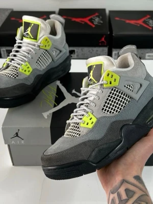 Air Jordan 4 Retro Neon Volt grå/gul - Snygga Air Jordan 4 Retro Neon Volt sneakers i grå mocka med svarta och neongula detaljer. Skorna har meshpaneler, synlig Air-sula och klassisk Jumpman-logga på plösen. Perfekta för dig som vill sticka ut med en unik och sportig look.