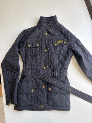 Svart quiltad jacka från Barbour - Vintage international Barbour jacka med bälte i midjan och gulddetaljer. Värde upp mot 2 000. Lite större i storleken, skulle passa även en 34 enligt mig. Finns i Malmö om man vill prova. 