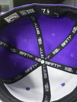 Lila New Era 59FIFTY NY keps - Säljer en lila New Era 59FIFTY keps med klassisk New York Yankees-logga i vitt framtill. Kepsen har rak skärm och broderad logga på sidan. Tillverkad i bomullsmix och har en snygg kontrast mellan lila och vitt.