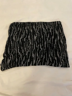 Svartvit mönstrad tubtopp  - En svart tubtopp med vitt prickigt mönster i vertikala linjer. Materialet är mjukt och stretchigt, vilket gör den enkel att styla till olika looks.