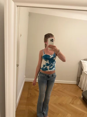 Blåvit tie-dye linnetopp - Trendig blåvit linnetopp med tie-dye mönster och smala axelband. Croppad modell som passar perfekt till jeans eller kjol. Sval och skön för varma dagar, perfekt för en avslappnad och cool stil. Den har ingen storlek i sig men passar mig och har ofta xs på toppar den sitter väldigt bra 