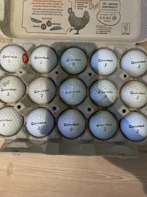 TaylorMade vita golfbollar i kartong - Säljer 15 vita golfbollar från TaylorMade, förvarade i en äggkartong. Bollarna har olika siffror tryckta på sig och är tillverkade i slitstarkt material. Perfekt för golfentusiasten som vill fylla på med fler bollar till rundan.Visaa är i bra skick och nytt skick men några är missfärgade