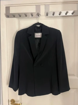 Svart figursydd kavaj från InWear - Svart kavaj från InWear med figursydd passform, axelvaddar och två knappar framtill. Använd fåtal gånger, i mycket bra skick! 