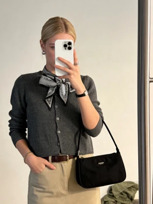 Mörkgrå ribbstickad kofta - Stilren mörkgrå ribbstickad kofta med knappar framtill. Koftan har en klassisk passform och är perfekt att styla med en scarf eller skjorta. Materialet känns mjukt och bekvämt, och den neutrala färgen gör den lätt att matcha.