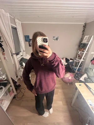 Vinröd hoodie med ficka - En vinröd hoodie med stor magficka och huva. Klassisk modell med dragsko i huvan och ribbade muddar vid ärmslut och nederkant. Perfekt för en avslappnad och chill stil. Materialet är mjukt och skönt.