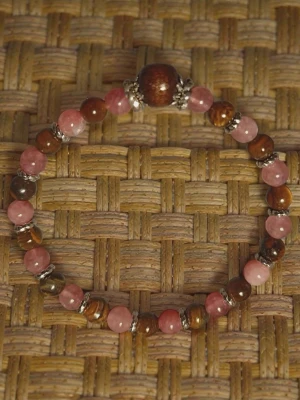 Armband med rosa sten pärlor och bruna tiger pärlor - Snyggt armband med pärlor i rosa och bruna toner, dekorerat med små silvriga detaljer mellan pärlorna. Armbandet har en större brun pärla som mittpunkt och är elastiskt för enkel användning. Perfekt accessoar för att lyfta din stil.