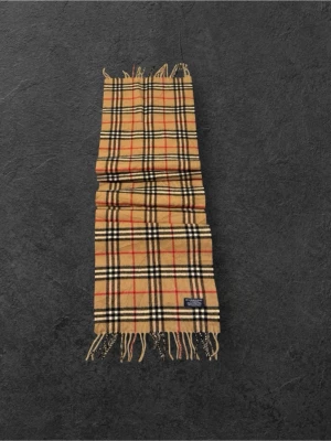 Beige rutig halsduk från Burberry - Klassisk beige halsduk från Burberry i mjuk ull med det ikoniska rutmönstret i svart, vitt och rött. Halsduken har fransar i båda ändar och en vävd Burberry-etikett. Perfekt accessoar för att lyfta din outfit.