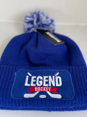 Legend Hockey mössa med tofs (4 st olika färger) - Säljer 4 st stickade mössor från Legend hockey med broderad patch. Finns i blått, svart, blå-grå och grått, med stor tofs upptill. Perfekt för dig som gillar hockey och vill ha en sportig stil.