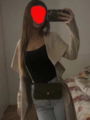 Beige lång rock med öppen front - Stilren beige rock med öppen front och avslappnad passform. Rocken har långa ärmar och faller snyggt längs kroppen. Perfekt att slänga över en outfit för en trendig look. Passar till både jeans och klänning.