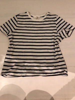 Randig t-shirt från H&M XS - Säljer en klassisk vit t-shirt med svarta horisontella ränder från H&M i storlek XS. T-shirten har korta ärmar och är gjord i mjuk bomull, perfekt för en chill och enkel stil. Passar till allt och är superenkel att matcha.