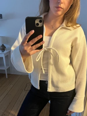 Vit ribbad kofta med knytband - Säljer en stilren vit ribbad kofta med knytband framtill och breda ärmar. 