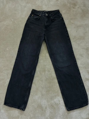 Svarta raka jeans från Pull&Bear - Säljer ett par svarta jeans från Pull&Bear med rak passform och hög midja. Jeansen har klassisk femficksdesign, silverfärgad knapp och nitar i kopparfärg. Materialet är kraftig denim i 100% bomull. Perfekta för en avslappnad och trendig look.