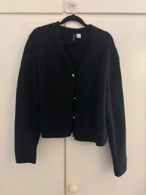 Svart kofta med guldfärgade knappar - Säljer en snygg svart kofta med guldknappar från h&m🥰Koftan är i storlek L men jag skulle säga att den även passar för S och M🤗