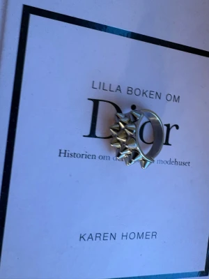 Silvrig ring med nitar - Cool ring i silverfärgad metall med flera små, spetsiga nitar runt hela bandet. Perfekt för dig som gillar en edgy och alternativ stil. Ringen har en bred design och sticker verkligen ut.