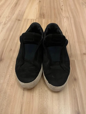 Mörkblåa clean 360  från Axel Arigato - Mörkblåa clean 360 sneakers från Axel Arigato med vit sula och minimalistisk design. Ovandelen är i mocka och skon har en låg profil utan snörning, vilket ger en clean och stilren look. Perfekta för dig som gillar enkel och modern stil. Lite slitna på hällen och där fram men inga större problem och funkar perfekt.