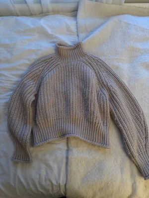 Beige polotröja från H&M - Säljer en chunky beige stickad polotröja från H&M. Tröjan har bred ribbstickning vid hals, ärmslut och nederkant samt en hög krage. Perfekt för lager på lager och riktigt mysig att bära under kyliga dagar.