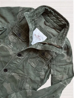 HOLLISTER FIELD JACKET - En extremt snygg och unik field jacket från Hollister med ett lätt camo mönster! Hör av dig vid frågor!