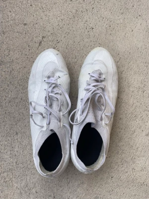 Vita Nike  fotbollsskor - Säljer ett par vita Nike Zoom fotbollsskor med snörning och låg profil. Skorna har en ovandel i syntetmaterial och dobbar i plast med grönaktig ton undertill. Perfekta för dig som vill ha lätta och snabba skor på planen.