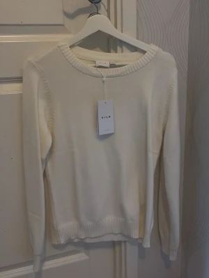 Vit stickad tröja från VILA - Klassisk vit stickad tröja från VILA med rund halsringning och ribbade muddar vid ärmslut och nederkant. Aldrig andvänt!💞 pris kan diskuteras!