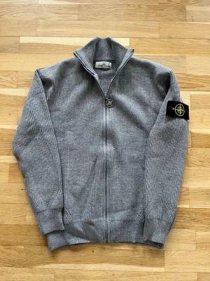 Grå stickad ziptröja Stone Island - En superunik tröja! Knappt anvand, i nyskick. Tröjan ar tjock, varm och perfekt för våren, både för en fin och bekväm look. Tröjan ar för män. Den är i storlek M. Passar dig som ar ungefar 170-185 cm lång och väger 60-80kg. Hör gärna av dig om du har några frågor eller funderingar!