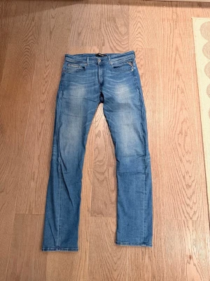 Replay grover ljusblå - Säljer ett par blå slim fit jeans med snygg tvätt. Materialet är denim med lätt stretch för skön passform. Modell grover storlek 32/34