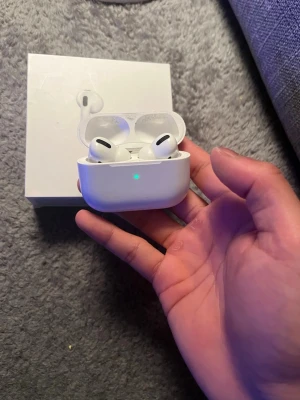 Apple AirPods Pro trådlösa hörlurar - Säljer ett par vita Apple AirPods Pro med laddningsetui. De är trådlösa in-ear hörlurar med silikontoppar och kompakt design. Perfekta för musik, samtal och träning. Kommer med originalförpackning. Snygg och stilren look som passar till allt.