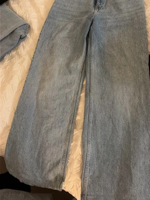 Ljusblå raka jeans i klassisk modell - Säljer ett par ljusblå jeans med rak passform och hög midja. Jeansen har fem fickor och är tillverkade i klassisk denim. Perfekta för en avslappnad och trendig look. Inga synliga loggor eller märken på byxorna.