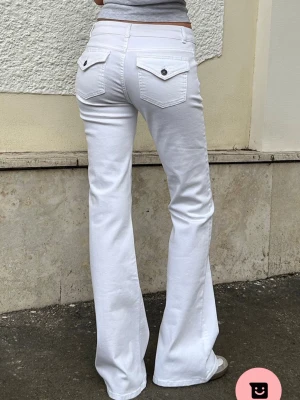Vita bootcut jeans med fickdetaljer - Säljer ett par vita bootcut jeans med snygga fickor bak och knappdetaljer. Jeansen har låg midja och är från Subued. Skriv om ni vill ha egna bilder. Bara att höra av dig om du har några frågor!🥰