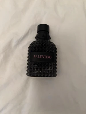 Valentino  - Snygg parfym från Valentino i en svart, nitat flaska med cool struktur. Flaskan har en modern design med Valentino-loggan i rosa på framsidan. Perfekt för dig som gillar exklusiva och trendiga dofter.