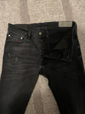 Diesel jeans - Mörkgrå/svarta diesel jeans med slitningar i storlek 29 slimfit i bra skick