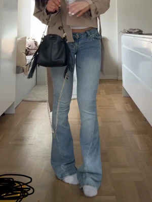 Ljusblå bootcut jeans med låg midja - Säljer ett par ljusblå bootcut jeans med låg midja och klassisk femficksdesign. Jeansen har en avslappnad passform över låren och utsvängda ben. Perfekta för en trendig och avslappnad stil.