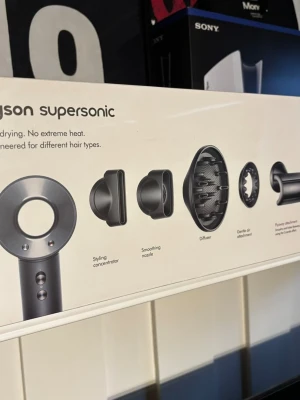 Dyson Supersonic hårfön med tillbehör - Säljer en Dyson Supersonic hårfön i silver med fem olika stylingtillbehör: stylingkoncentrator, smoothing nozzle, diffuser, gentle air attachment och flyaway attachment. Modern design i metall och plast, perfekt för olika hårtyper och stylingbehov.