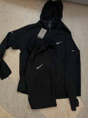 Nike Windbreaker Tracksuit- svart stl S Ny skick - Clean Nike windbreaker tracksuit i svart — ett lätt och funktionellt set som funkar lika bra till träning som streetwear. Andningsbart material och bekväm passform gör den till ett säkert val 🔥