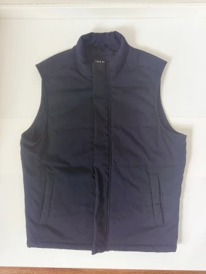 Zara väst mörkblå herr – strl M – modern stil - Stilren mörkblå väst från Zara – ett perfekt plagg för en clean och modern look.  ✔ Enkel och stilren design ✔ Perfekt för layering ✔ Passar både casual och uppklätt ✔ Fint skick  Perfekt för dig som vill komplettera garderoben med ett snyggt och användbart plagg.