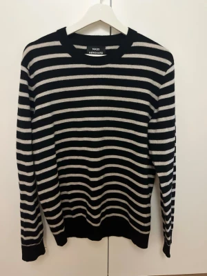 Randig stickad tröja Mads Nørgaard - Snygg stickad tröja från Mads Nørgaard med svarta och vita horisontella ränder. Tröjan har rund halsringning, långa ärmar och ribbade muddar vid ärmslut och nederkant. Perfekt för dig som gillar klassisk men trendig stil. Den är i storlek XL men passar mer M skulle jag säga. Nypris 1499 men säljer endast för 400kr. Skriv vid fler frågor!
