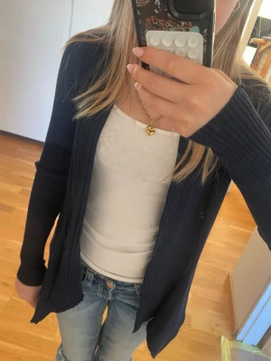 Mörkblå ribbad kofta från Esprit - Snygg mörkblå ribbad kofta från Esprit med öppen front och långa ärmar. Perfekt att slänga över en topp eller t-shirt. Koftan är i mjukt stickat material och har en klassisk, enkel design som passar till det mesta.