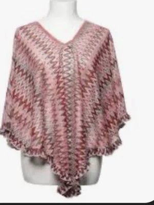 Mönstrad poncho brunt - Snygg sjal med zickzackmönster i brunt och beige toner. Sjalen har en V-ringad form och vågig kant, perfekt att slänga över axlarna för en cool look. Materialet känns lätt och luftigt, vilket gör den enkel att styla till olika outfits.poncho som säljer det är bilden 2 