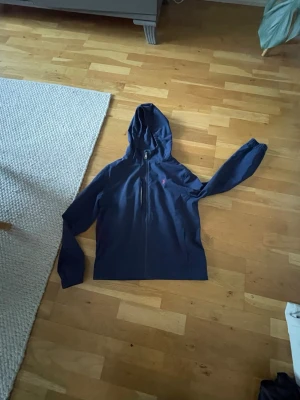 Mörkblå vindjacka med huva - Snygg mörkblå vindjacka från Polo Ralph Lauren med dragkedja framtill och huva. Jackan har en diskret logga på bröstet och är tillverkad i ett lätt och smidigt material som passar perfekt för blåsiga dagar. Enkel och stilren design. Storleken är L/G vilket är en barn storlek! I vuxen storlek sitter den XS-S! Det är ett liten brännskada framtill precis vid kragen! (Kolla bild 2)😄