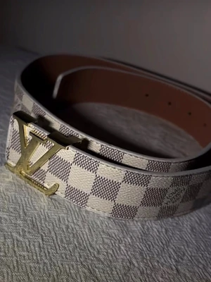 L-V bälte - Stilrent bälte i ljus design – helt nytt  Säljer ett snyggt bälte i ljus rutmönstrad design med guldfärgat spänne. Bältet är helt nytt och oanvänt, i perfekt skick.  Den ljusa färgen tillsammans med det eleganta spännet gör det till en perfekt accessoar som lyfter både vardags- och festoutfits.