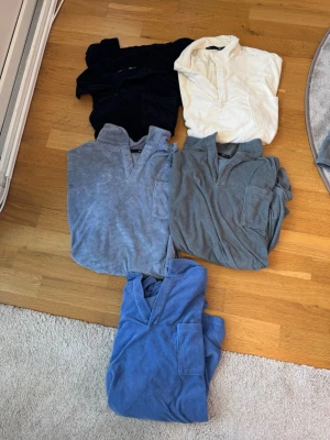 Fem frotté t-shirts med krage och frotté shorts - Fem t-shirts från lager 157 i frotté, med kort ärm, krage och bröstficka. Färgerna är svart, vit, ljusblå, grå och blå. Perfekta för en chill och avslappnad stil, med mjukt material som känns skönt mot huden. Och ett par shorts