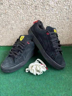 Svarta Puma Ferrari sneakers i mocka - Svarta sneakers från Puma i samarbete med Ferrari, tillverkade i mocka med svarta sulor. Skorna har röda detaljer, Ferrari-logga på plösen och vit sidostrip med röd kant. Extra vita skosnören medföljer. Perfekta för dig som gillar sportig och stilren design. Den är lite använt som du ser på bild 4 är de bak så på båda men annars är den fortfarande i bra skick. Jag kan diskutera vid snabbäfare. 