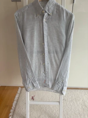 Ljusgrå linneskjorta från Stenströms - Snygg ljusgrå skjorta från Stenströms i linne med klassisk krage och knappar framtill. Broderad logga i orange vid knappslån. Fint skick, M
